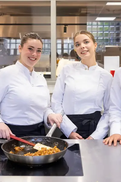 Studenten koken met plezier samen tijdens een praktijkles