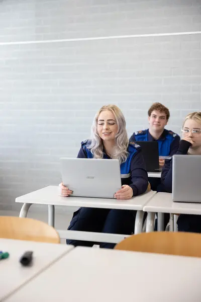 Student Veiligheidscollege in uniform achter laptop in klas