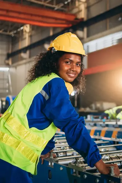 Vrouw met geel hesje en gele helm op staat voor een grote machine