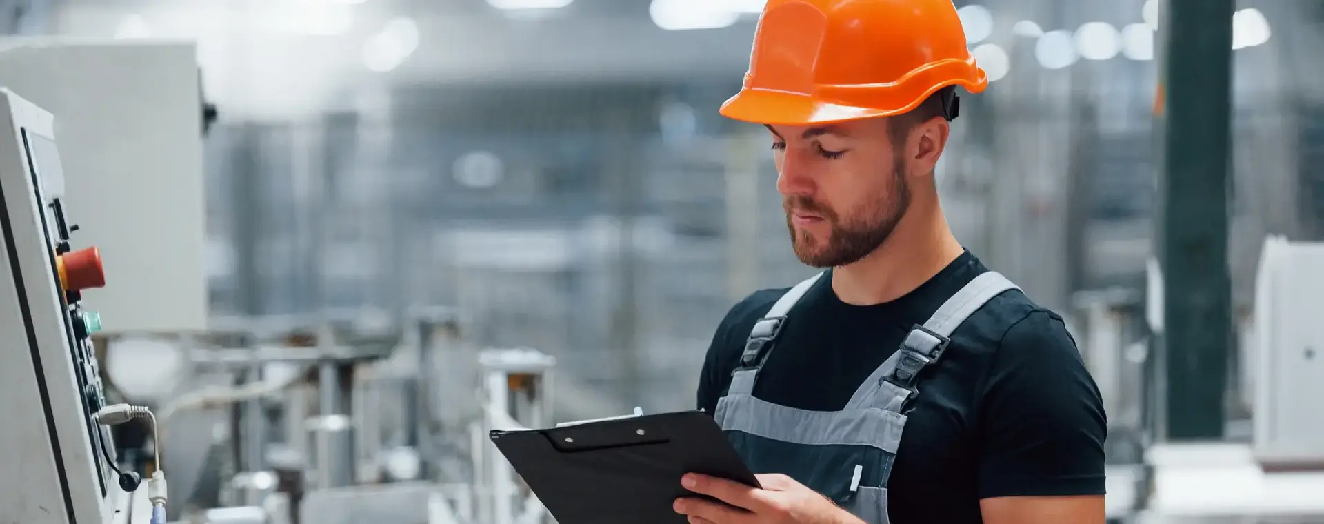 Man met helm en schrijfboard controleert machine