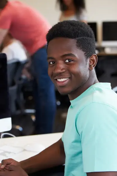 Student achter Imac kijkt glimlachend de camera in.