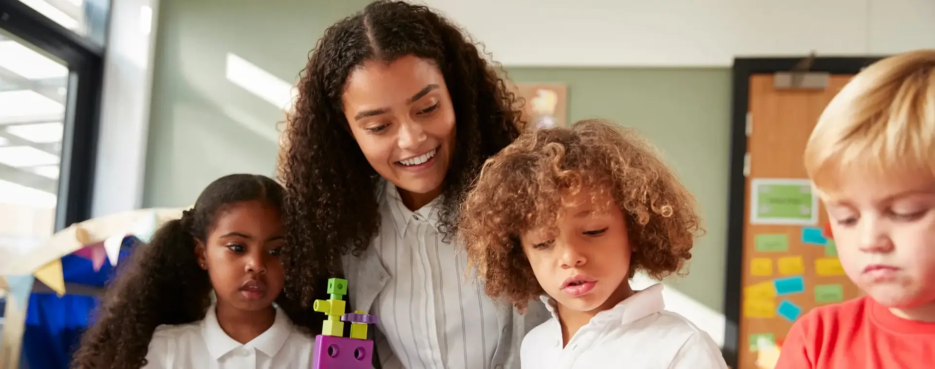 Een jonge docent begeleidt een groep kleuters die samen spelen en leren.