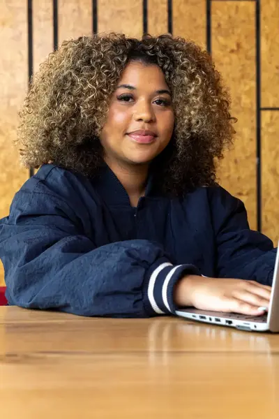 Meisje met grote bos krullen achter laptop