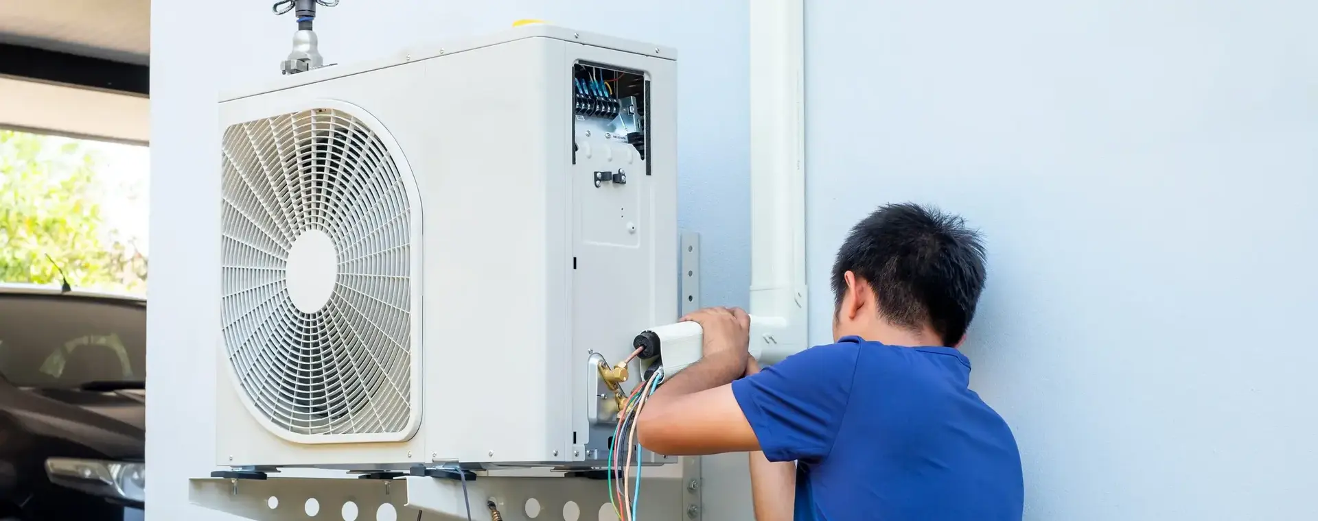 Een student werkt geconcentreerd aan een airconditioninginstallatie buiten. De foto straalt vakmanschap en technische vaardigheden uit.