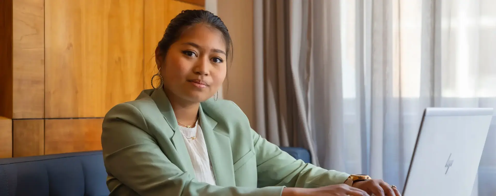 Meisje in groen jasje zit achter een laptop