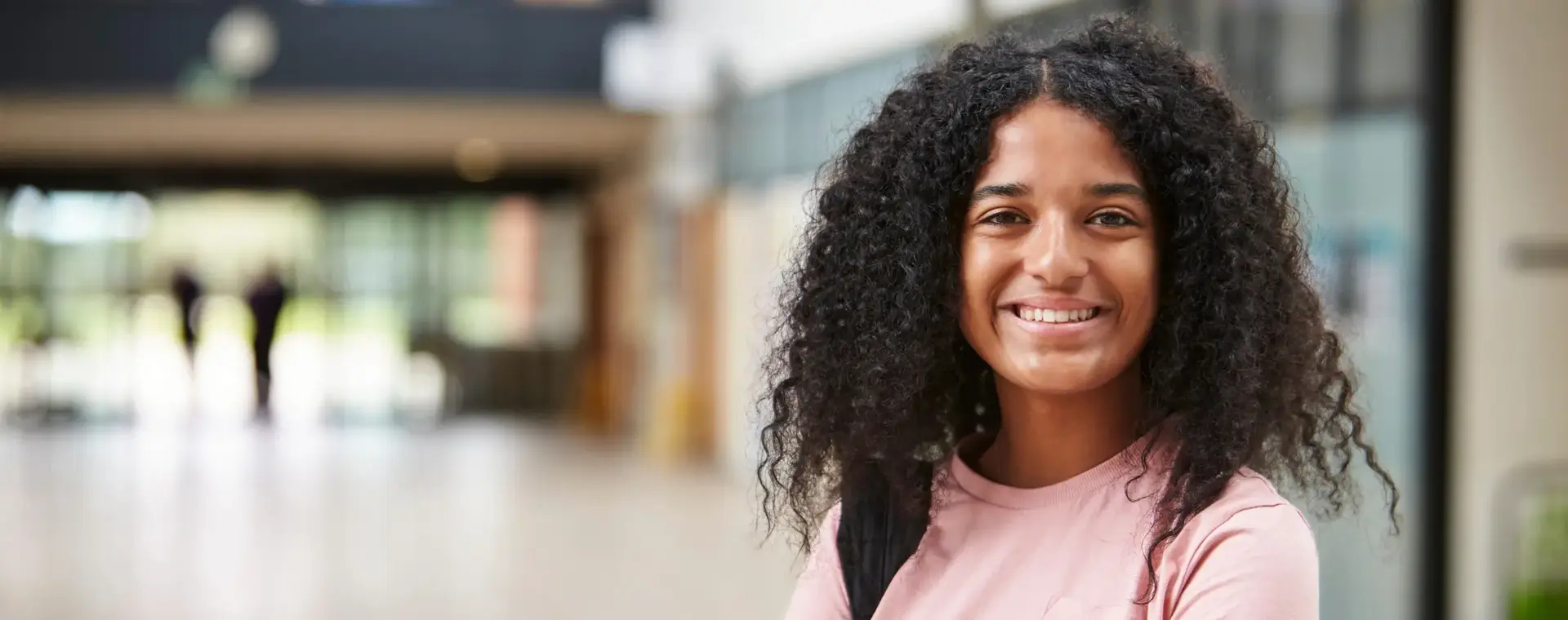 meisje in een roze t-shirt staat in de hal van een school
