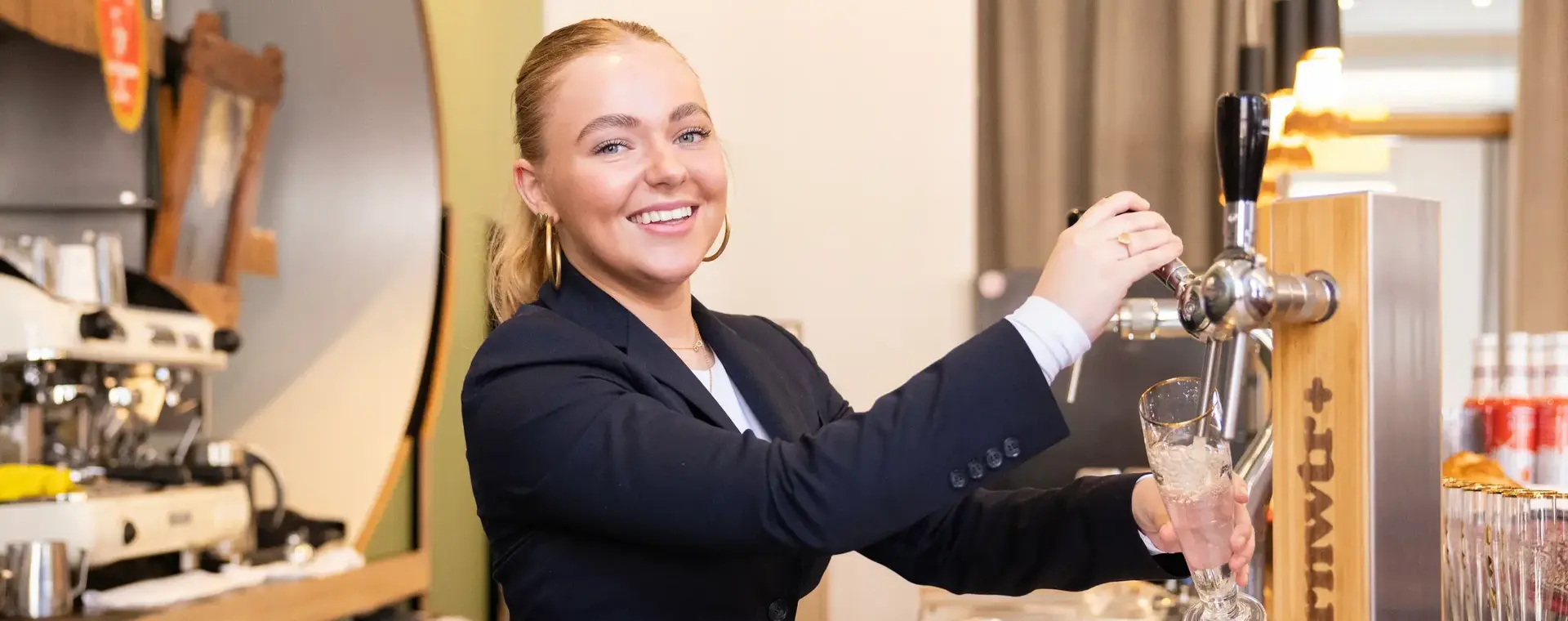 Horeca medewerker tapt een drankje achter de bar