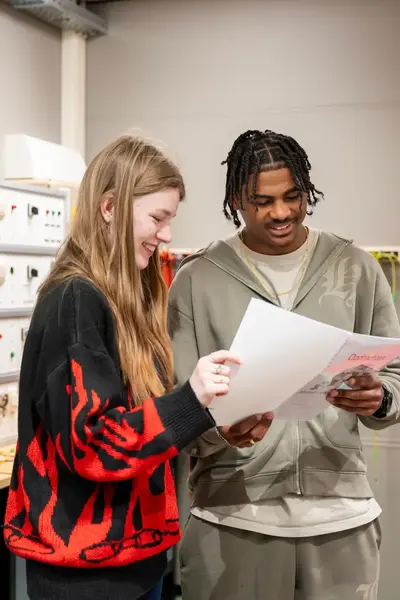 Techniekstudenten bestuderen opdrachten in praktijklokaal.