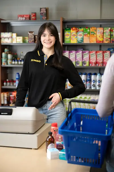 Medewerker van Jumbo staat achter de kassa in een winkel.