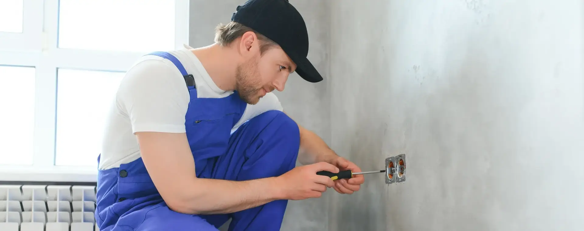 Student in werkkleding werkt aan een stopcontact in een woning