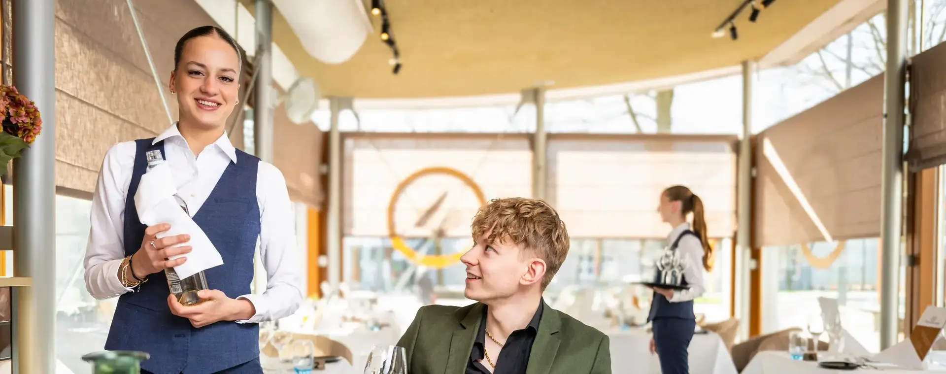 Studenten in een restaurantschool oefenen met serveren van wijn in een chique restaurantsetting