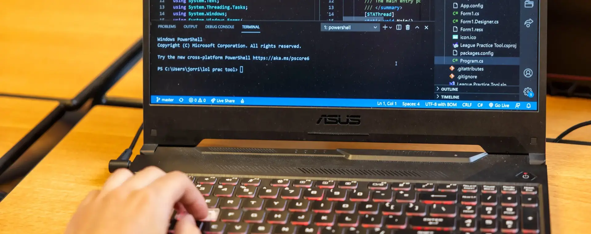 Laptop met programmeeromgeving en hand op het toetsenbord