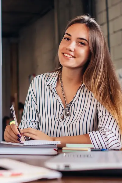 Studente achter bureau schrijft op kladblok